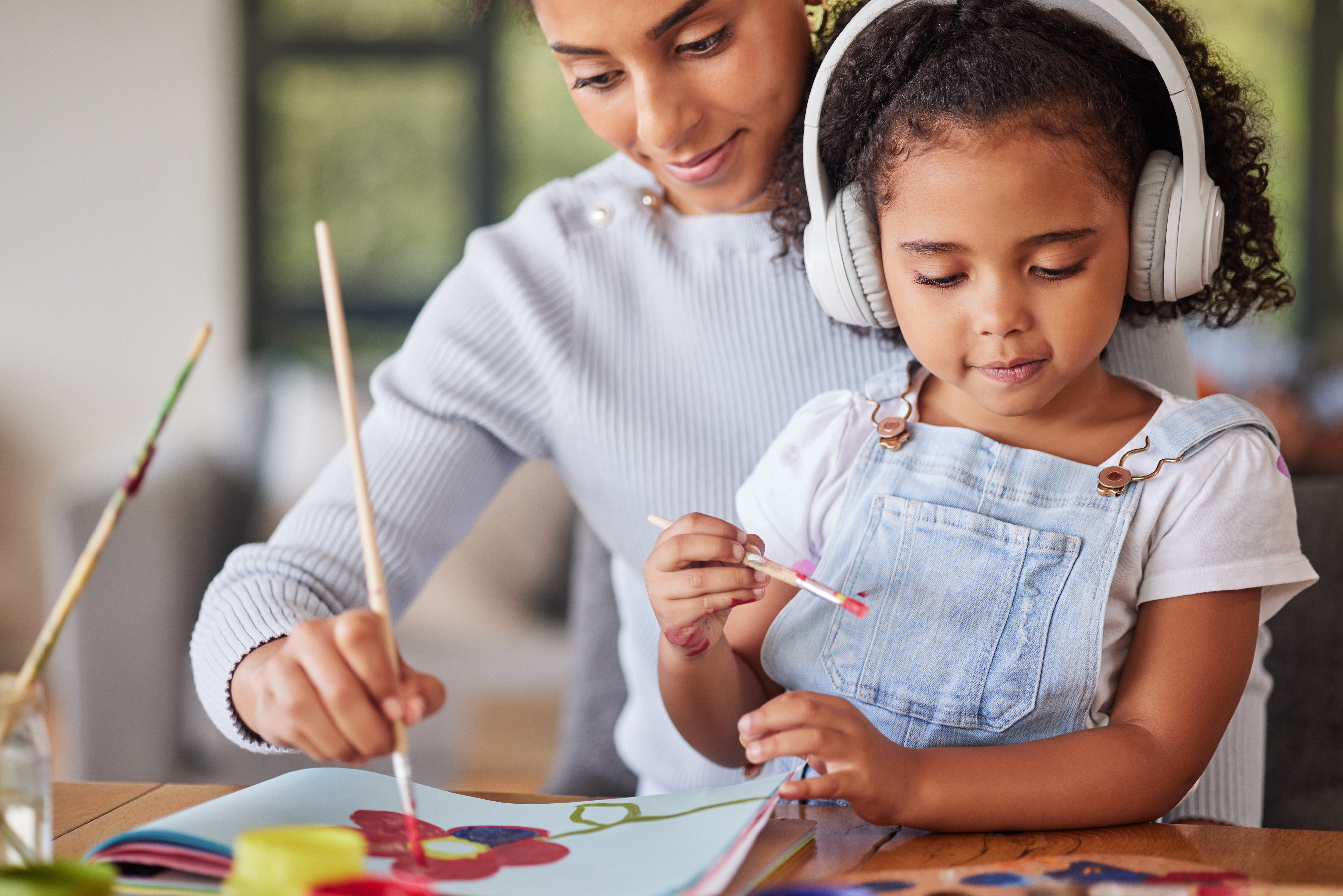 adult working with child wearing headphones