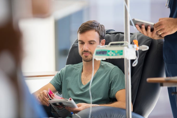 young man getting IV immunotherapy and reading